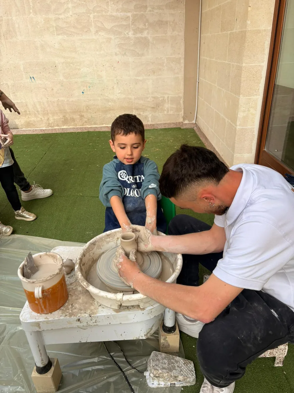 Un bambino al tornio seguito da un maestro